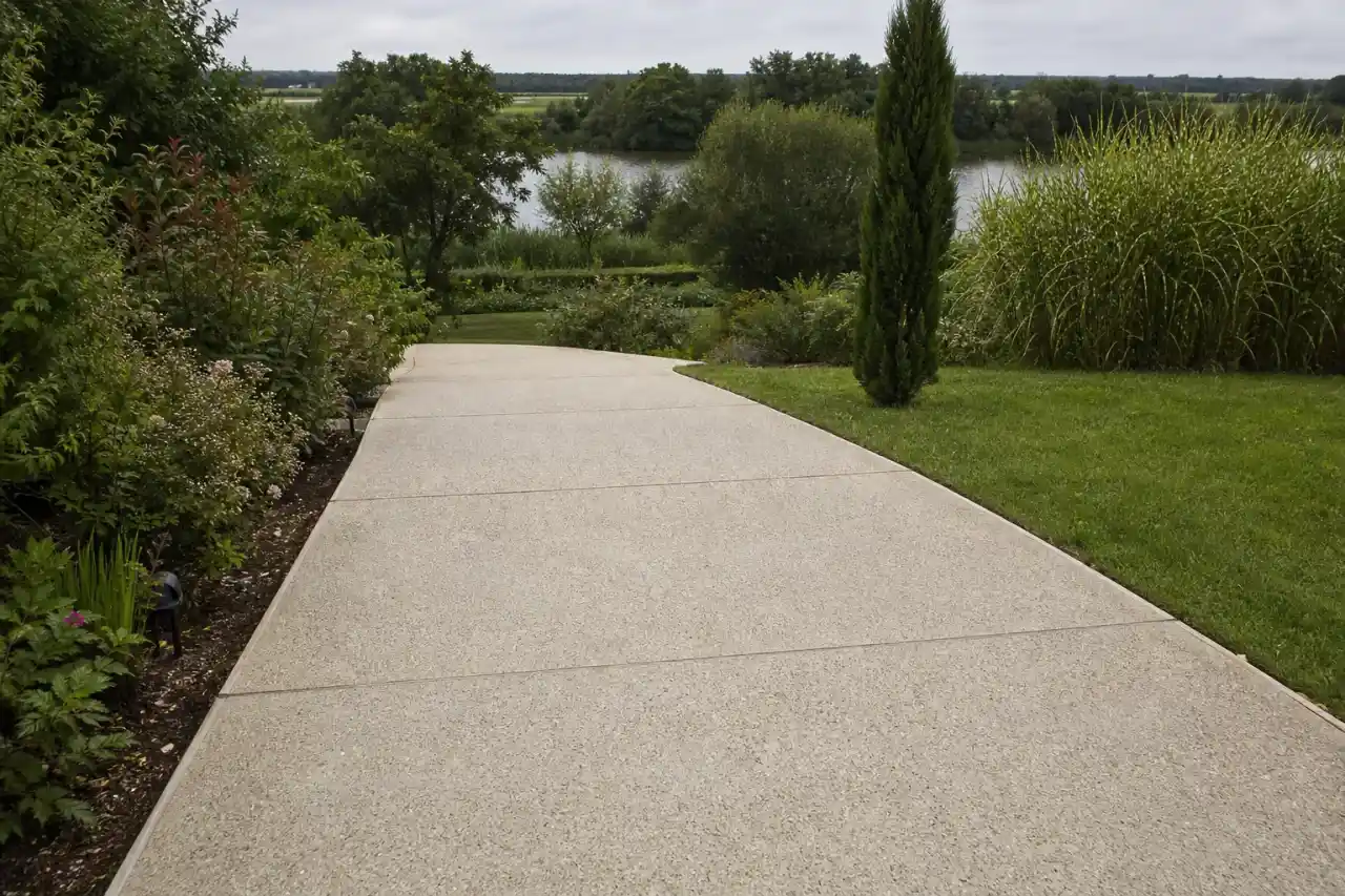 Allée en béton désactivé finie descendant en léger dévers dans un jardin castelroussin, joints de fractionnement visibles, bordures nettes et pente d'écoulement de l'eau vers l'Indre.