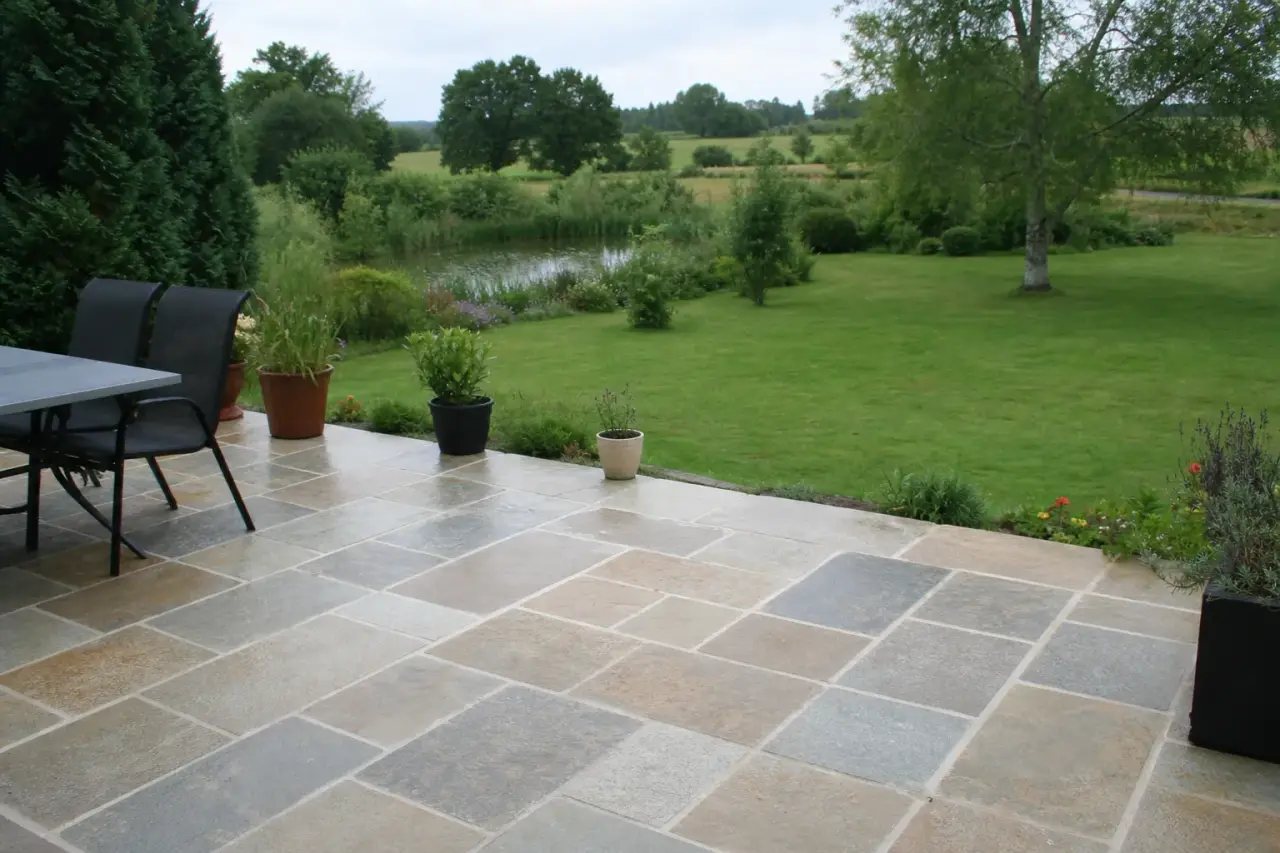 Terrasse en pierre naturelle terminée avec une légère pente d'écoulement, bordure soignée côté jardin, ambiance calme de plaine castelroussine près de Châteauroux.